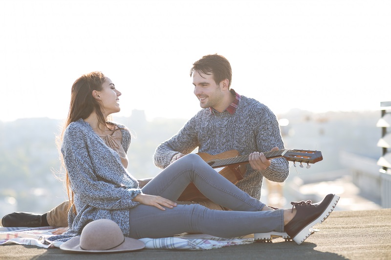 Young man and woman with guitar having fun outdoors Love and relations concept