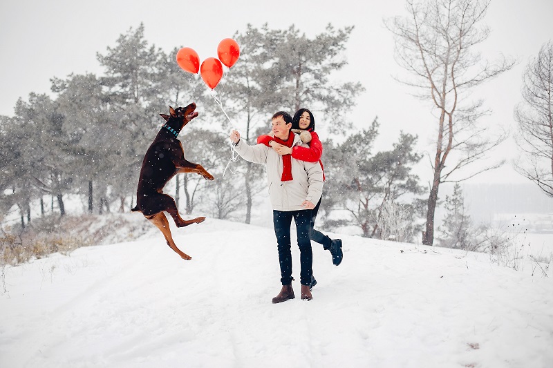 Young couple in a winter park. Man with a red sharf. Lady in a red jacket